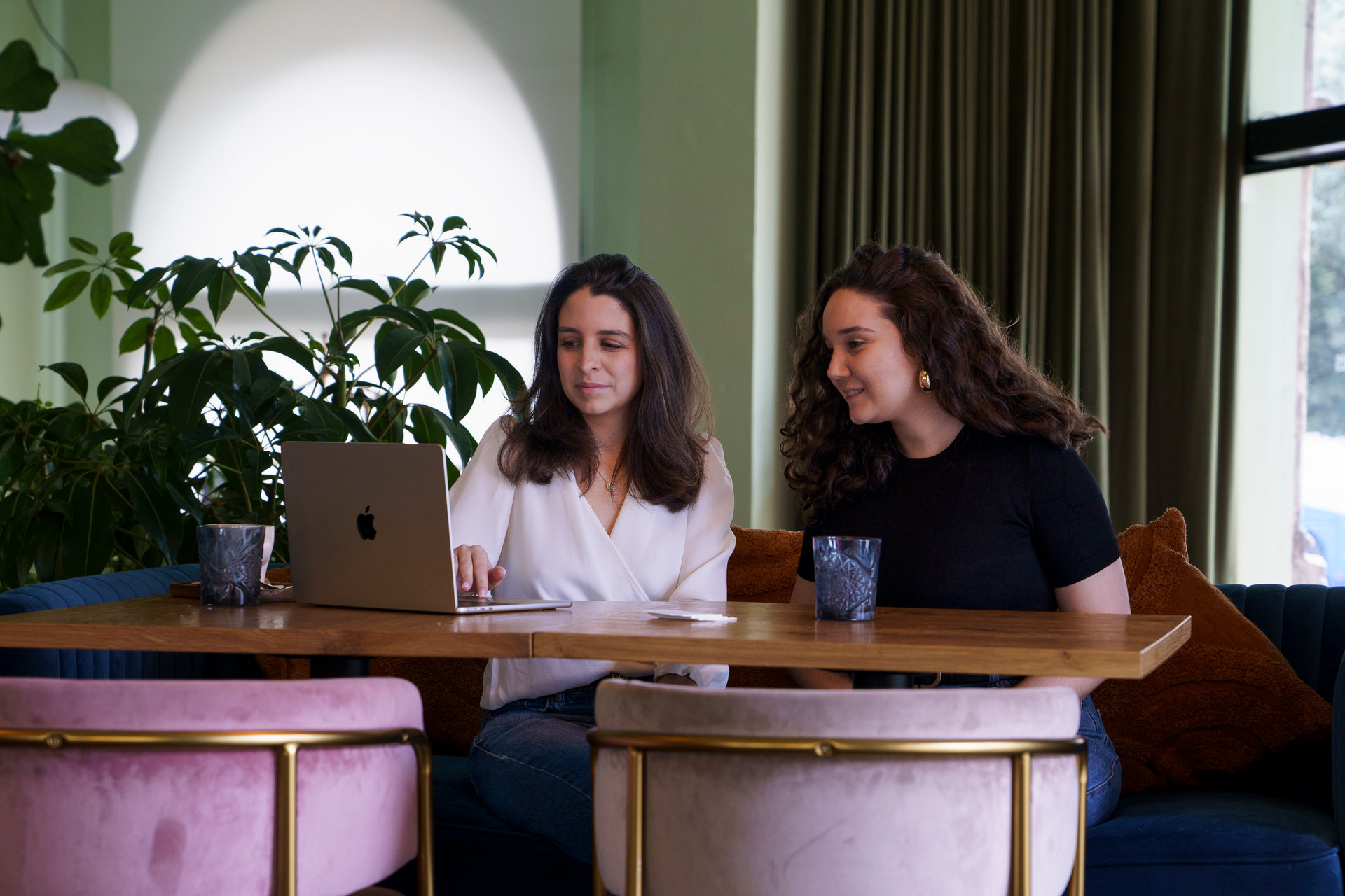 Carolina and Luiza planning an event together at a table with a laptop