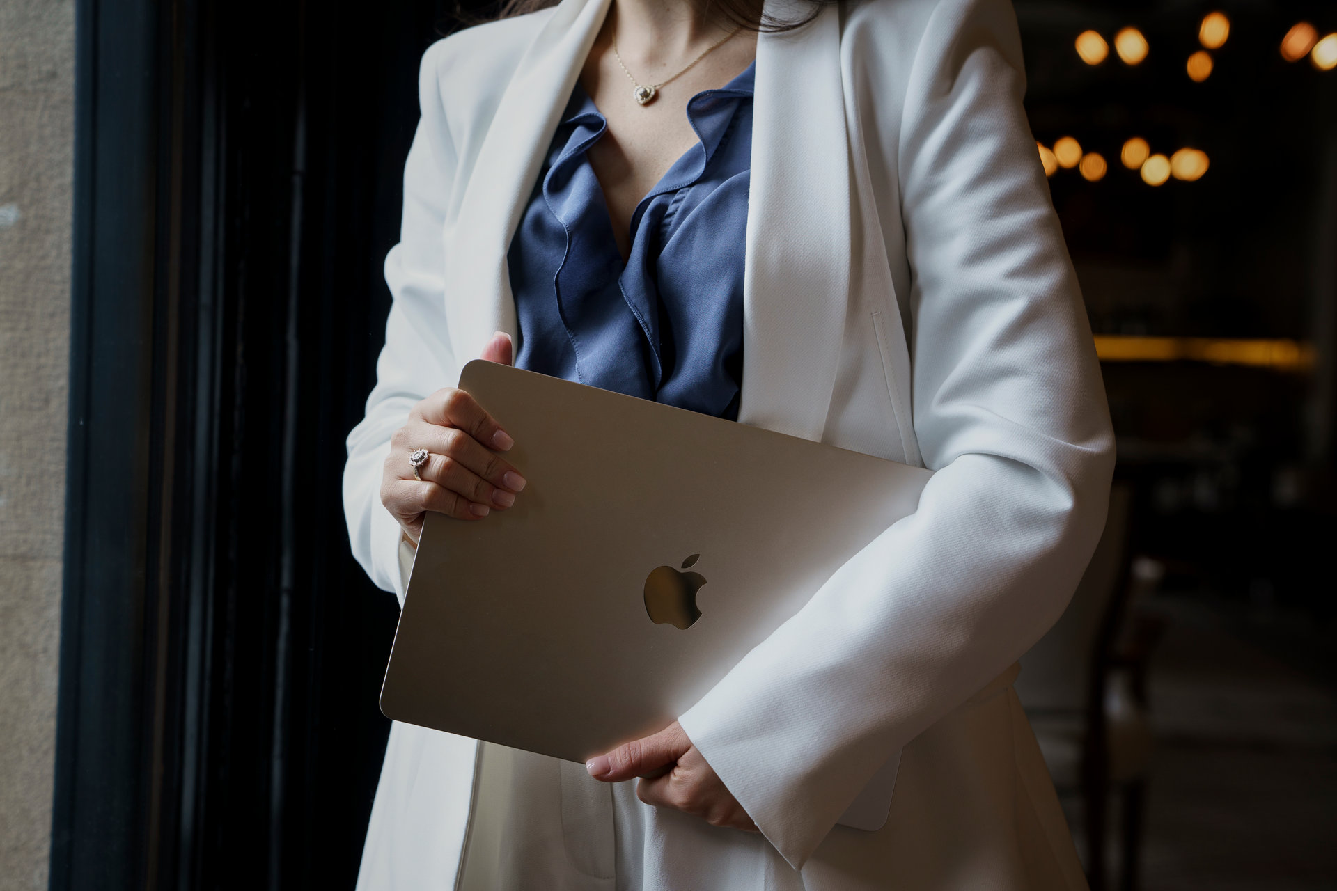Event planner in a white blazer holding a laptop