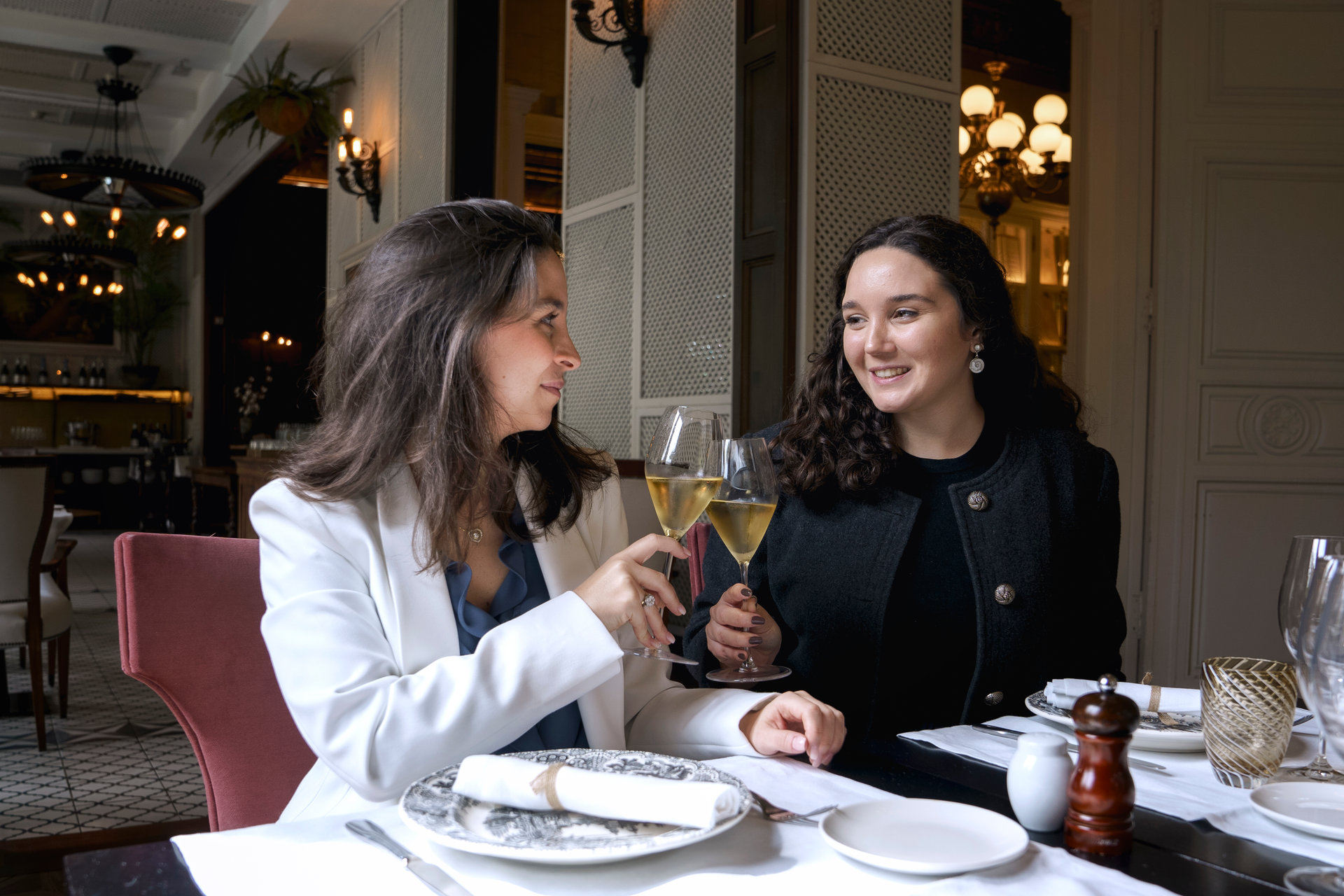 Two women toasting with wine at an elegantly set table